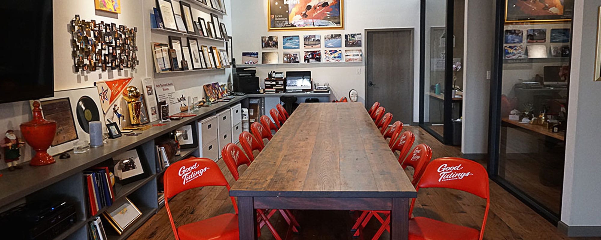 A long table sits with chairs around it in a casual office setting