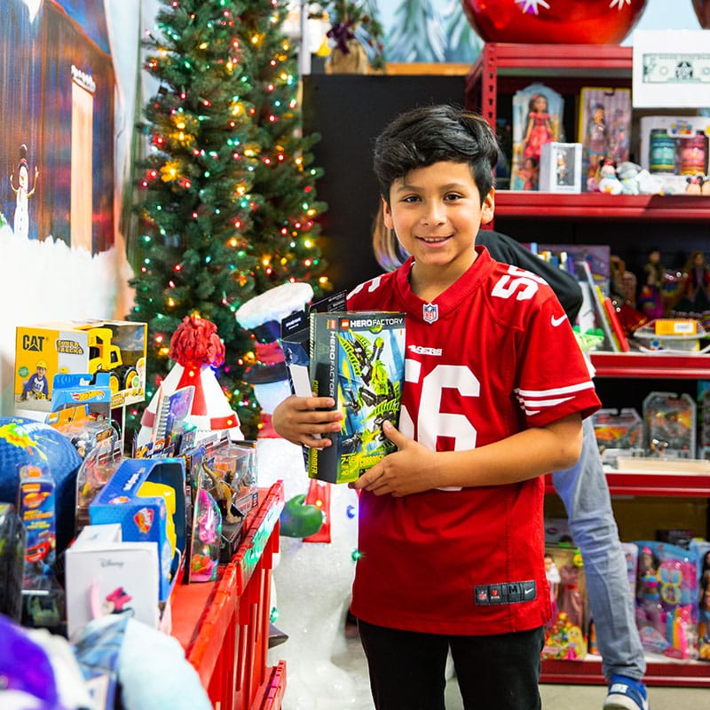 Child holding a toy surrounded by toys on a table at the Winter Wonderland event